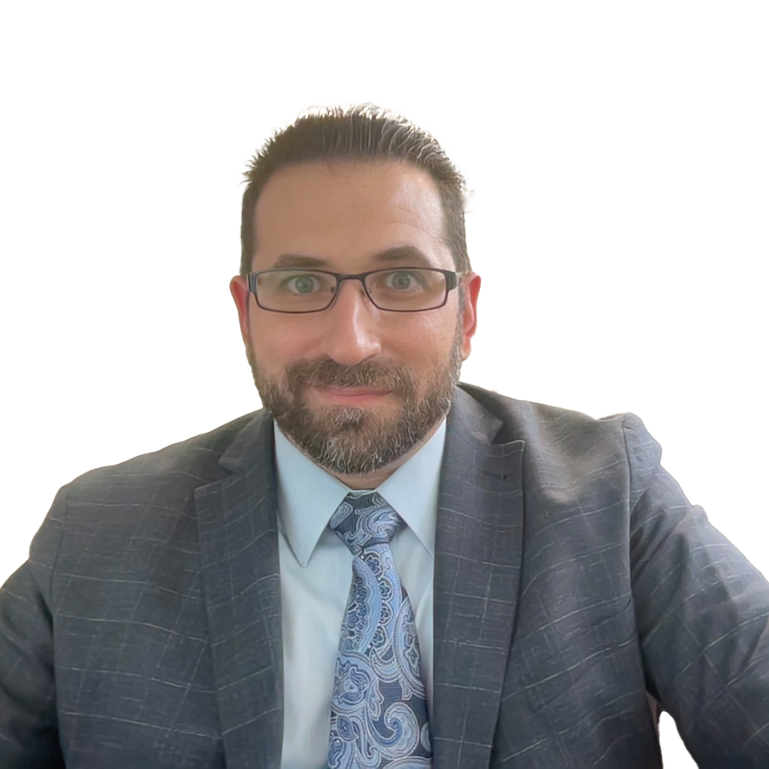 A bearded man with glasses is smiling while wearing a blue suit, light blue shirt, and paisley tie. The background is white and the lighting is bright, reflecting the professional yet approachable image of a digital marketing company on their "About Us" page.