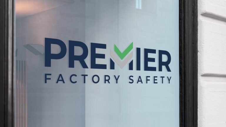 Signage on glass reads "PREMIER FACTORY SAFETY" with a green check mark incorporated in the design.