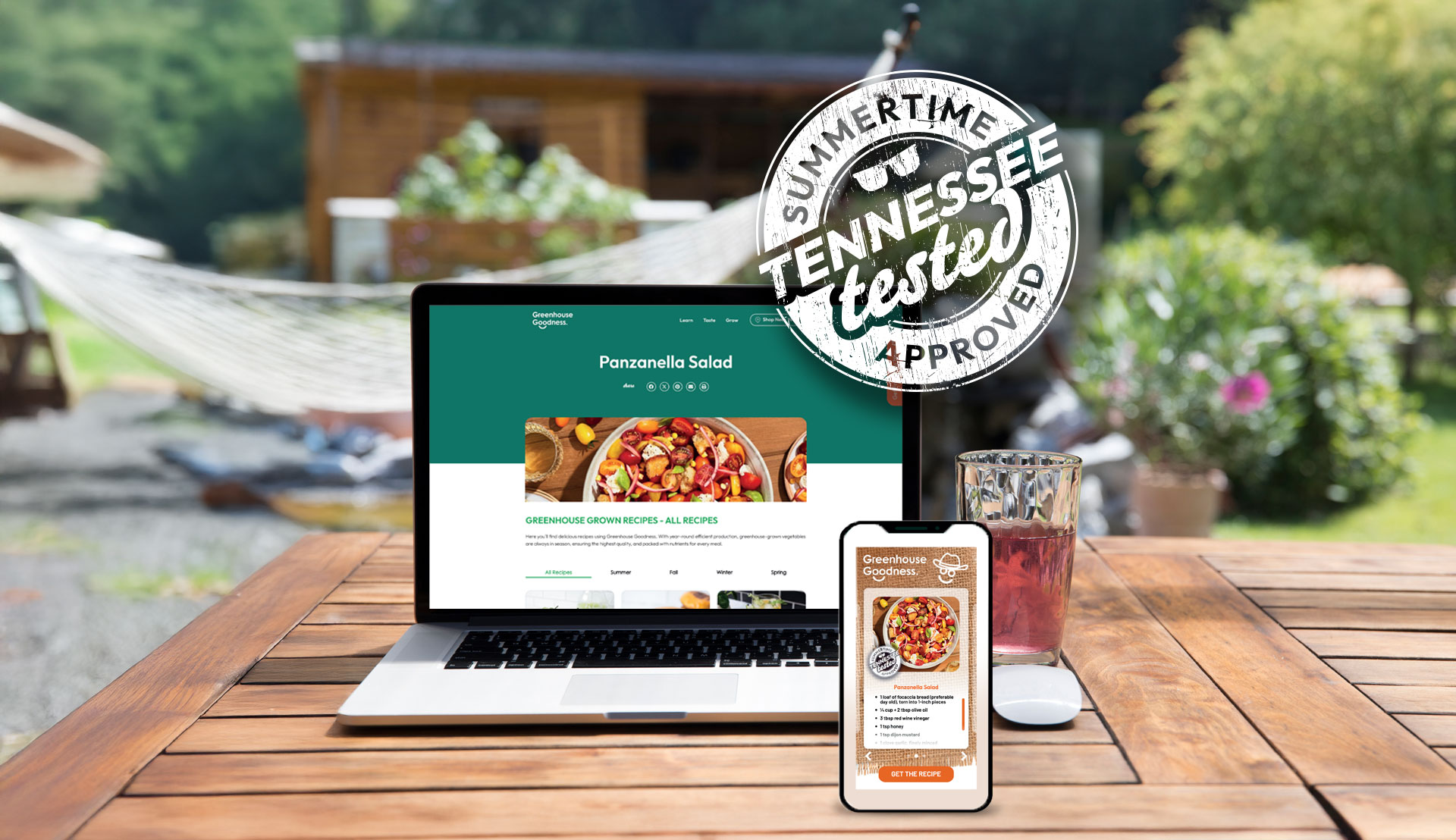 A laptop and smartphone displaying a Panzanella salad recipe sit on a wooden table outdoors, with a drink, hammock, and "Summertime Tennessee Tested Approved" stamp visible.